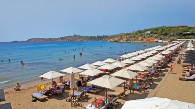 a beach with many umbrellas and people in the water at Αnna's Home 2 .Holidays in beautiful Athens in Athens
