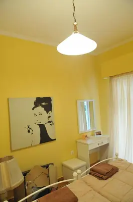 a bedroom with yellow walls and a bed and a lamp at Cozy ACROPOLIS in Athens