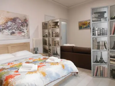 a bedroom with a bed and a couch and bookshelves at Koukaki-close to Acropolis(Stone apartment) in Athens