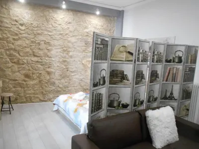 a room with a book shelf with shoes and a couch at Koukaki-close to Acropolis(Stone apartment) in Athens