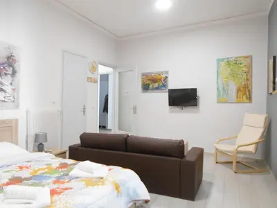 a bedroom with a bed and a couch and a tv at Koukaki-close to Acropolis(Stone apartment) in Athens