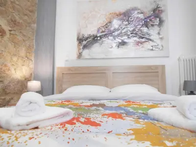 a bedroom with a bed with a painting on the wall at Koukaki-close to Acropolis(Stone apartment) in Athens