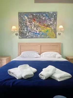 two towels on a bed with a painting on the wall at Koukaki-Acropolis roomy with a private veranda apt. in Athens