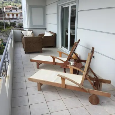 a patio with two chairs and a couch on a balcony at Modern apartment near Athens&Coast in Keratea