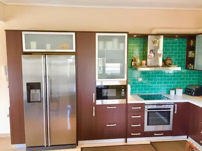 a kitchen with brown cabinets and a stainless steel refrigerator at Modern apartment near Athens&Coast in Keratea