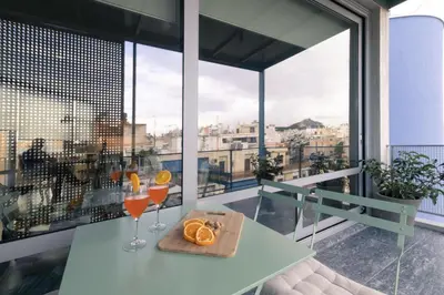 a table with two glasses of wine and oranges on a balcony at Athens BlueBuilding in Athens