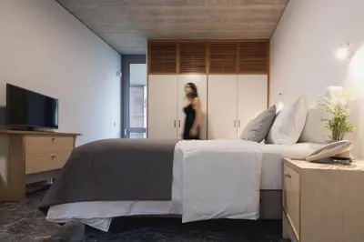 a woman is standing behind a bed in a bedroom at Athens BlueBuilding in Athens