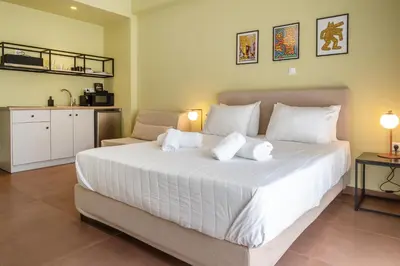 a bedroom with a large white bed and a kitchen at ATHENS STORIES in Athens