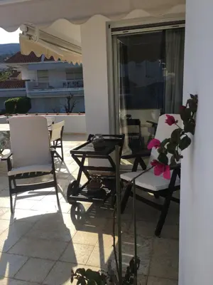 a patio with chairs and a table on a balcony at Bay watch Apartment close to the airport at PORTO RAFTI in Porto Rafti
