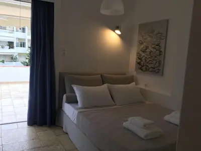 a bed with white pillows in a room with a window at Bay watch Apartment close to the airport at PORTO RAFTI in Porto Rafti