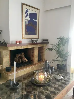 a living room with a fireplace and a table with a candle at Bay watch Apartment close to the airport at PORTO RAFTI in Porto Rafti