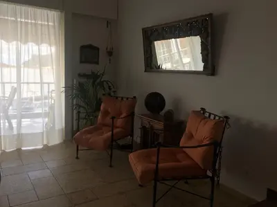 a living room with two chairs and a mirror at Bay watch Apartment close to the airport at PORTO RAFTI in Porto Rafti