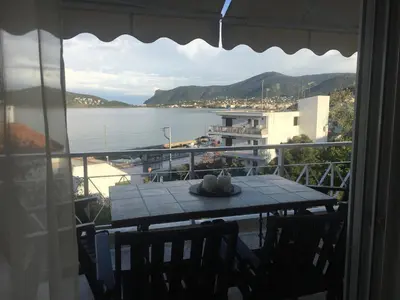 a table on a balcony with a view of the water at Bay watch Apartment close to the airport at PORTO RAFTI in Porto Rafti