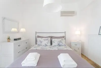a white bedroom with a large bed with two towels at Bay watch Apartment close to the airport at PORTO RAFTI in Porto Rafti
