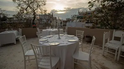 a table with white tables and chairs and the sunset at ATHENS City Center Historical Area in Athens