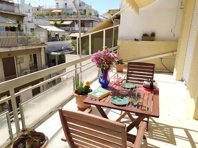 a table on a balcony with flowers on it at Renovated apartment close to Exarchia square in Athens