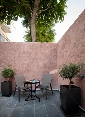 a patio with a table and two chairs and a tree at Plaka Arch Suites in Athens