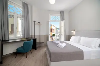 a bedroom with a bed and a desk and windows at Plaka Arch Suites in Athens