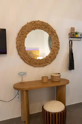 a mirror on a wall with a table and a stool at New seafront studio in Anavissos