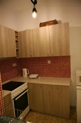 a kitchen with wooden cabinets and red tile on the wall at Marika Apartment in Athens