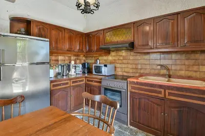 a kitchen with wooden cabinets and a stainless steel refrigerator at Light-filled home with Garden near Beach in Anavissos