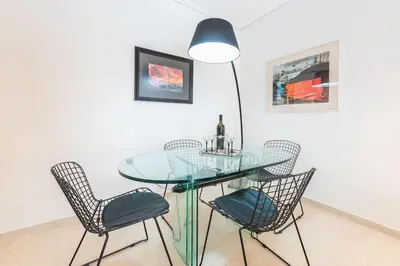 a glass table with chairs and a lamp in a room at Seaside Central Apartment in Athens