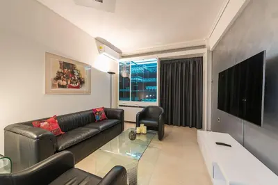 a living room with a black leather couch and a television at Seaside Central Apartment in Athens