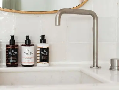 three bottles ofodorizers sitting on a shelf next to a sink at Coco-mat Athens BC in Athens