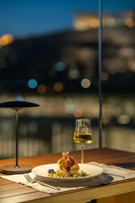 a plate of food and a glass of wine on a table at Coco-mat Athens BC in Athens