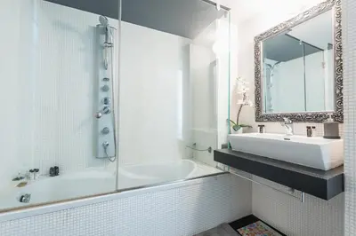 a bathroom with a tub and a sink and a mirror at Traveler's Dream 4 brdm Renovated Penthouse in Athens