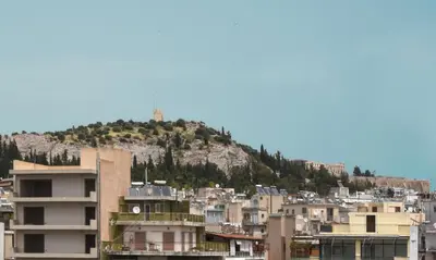 a group of buildings with a hill in the background at Koukaki Edge Penthouse•Acropolis & Filopappou view in Athens