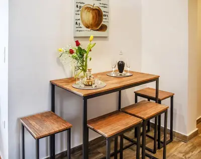 a table with three stools and a table with flowers at Koukaki Edge Penthouse•Acropolis & Filopappou view in Athens