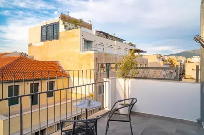 a balcony with two chairs and a view of a building at Mythos Luxury Suites in Athens