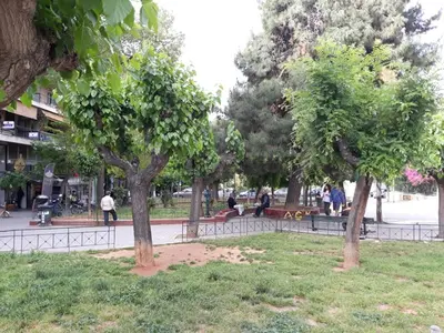 a park with trees and people sitting on benches at Fully renovated small & cosy studio in Athens