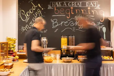 two men standing at a bar preparing food at Hotel Marina in Athens