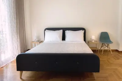 a bedroom with a large bed with a blue chair at Pnyka Apartment 2 in Athens