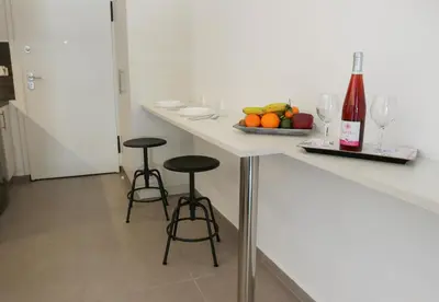a kitchen with a counter with two stools and a bowl of fruit at V36 Suites in Athens