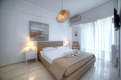 a bedroom with a large bed and a large window at L'appartement blanc dans le centre de Glyfada in Athens