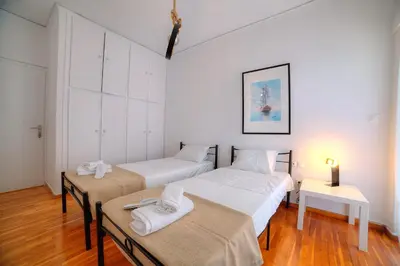 a bedroom with two beds and a table with towels at L'appartement blanc dans le centre de Glyfada in Athens