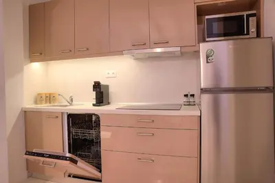 a kitchen with a stainless steel refrigerator and cabinets at L'appartement blanc dans le centre de Glyfada in Athens