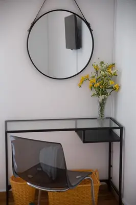 a mirror hanging above a desk with a chair at L'appartement blanc dans le centre de Glyfada in Athens