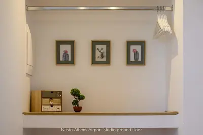 a wall with three pictures and a shelf with a plant at Nesto Athens Airport in Spáta