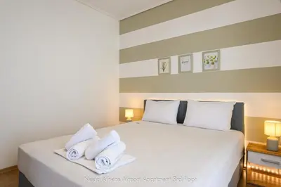 a bedroom with a white bed with towels on it at Nesto Athens Airport in Spáta