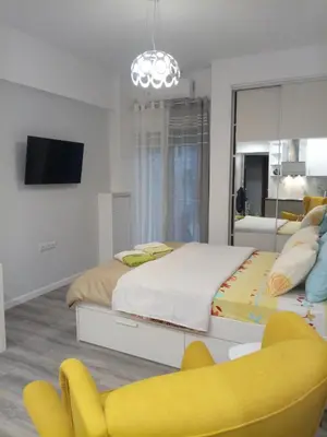 a bedroom with a large bed and a yellow chair at Cozy studio near Victoria metro station in Athens