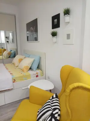 a bedroom with a bed and a yellow chair at Cozy studio near Victoria metro station in Athens
