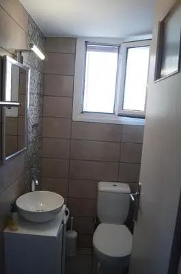 a bathroom with a toilet and a sink and a window at Sea Side Apartment in Palaiá Fókaia