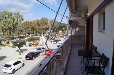 a balcony of a building with cars parked on a street at Sea Side Apartment in Palaiá Fókaia