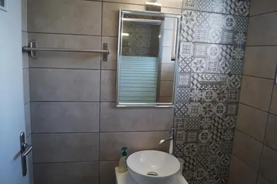 a bathroom with a sink and a mirror and a toilet at Sea Side Apartment in Palaiá Fókaia