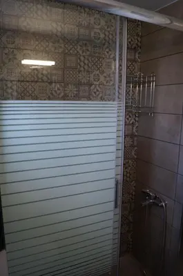a bathroom with a shower with a window and a shower door at Sea Side Apartment in Palaiá Fókaia