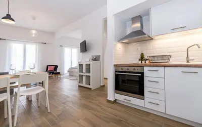 a kitchen and dining room with white cabinets and a table at Wide Comfy Studio Apartment Centrally Located In Thissio in Athens